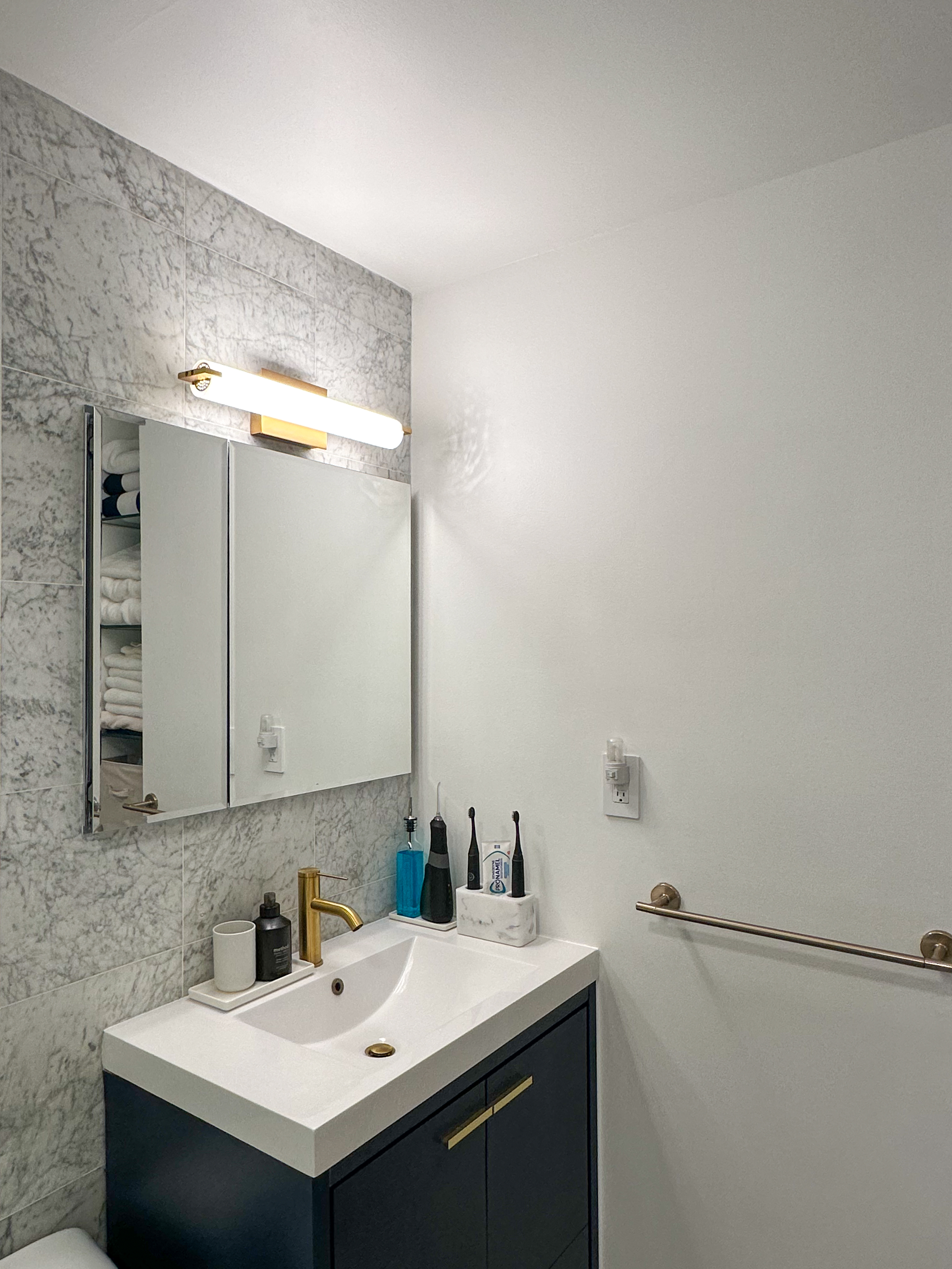 Bathroom — navy vanity, brass fixtures, Carrara marble tile